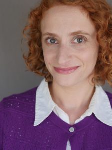 Becky Feldman portrait facing camera, wearing a purple sweater.